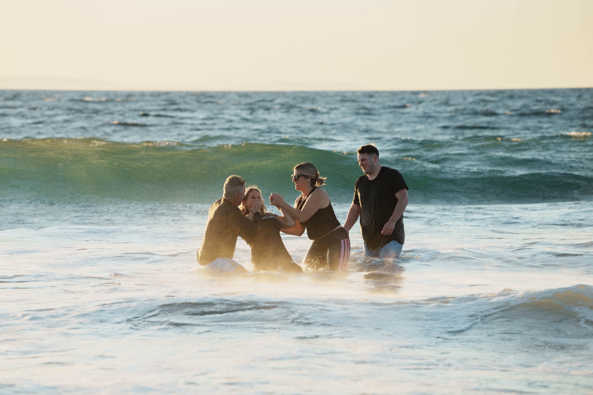 An ocean baptism at sunset during retreat