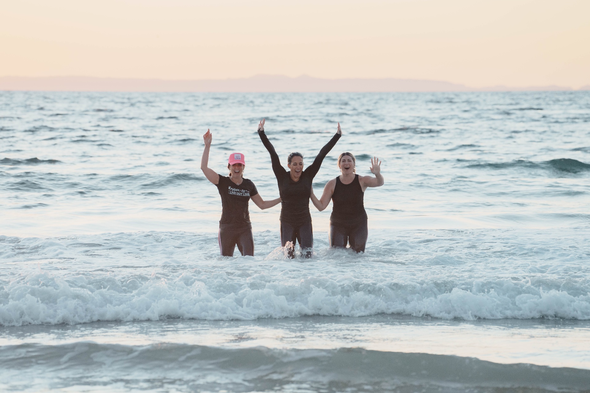 Three women celebrating in the ocean after baptism